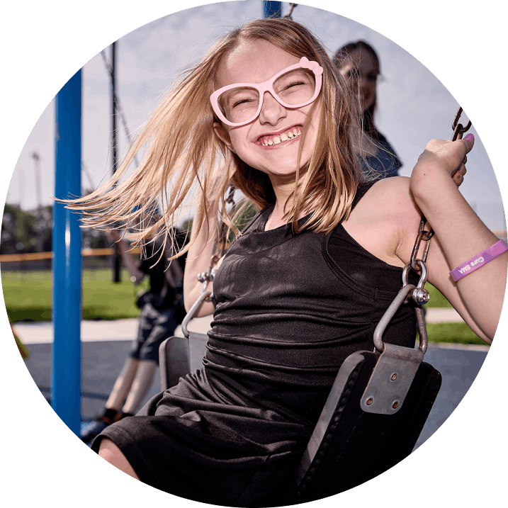 Lily, a child treated with ISEMBYLD, on a swing outdoors
